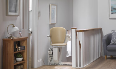 Woman on a Stannah stairlift at the top of the stairs on the first floor of the house